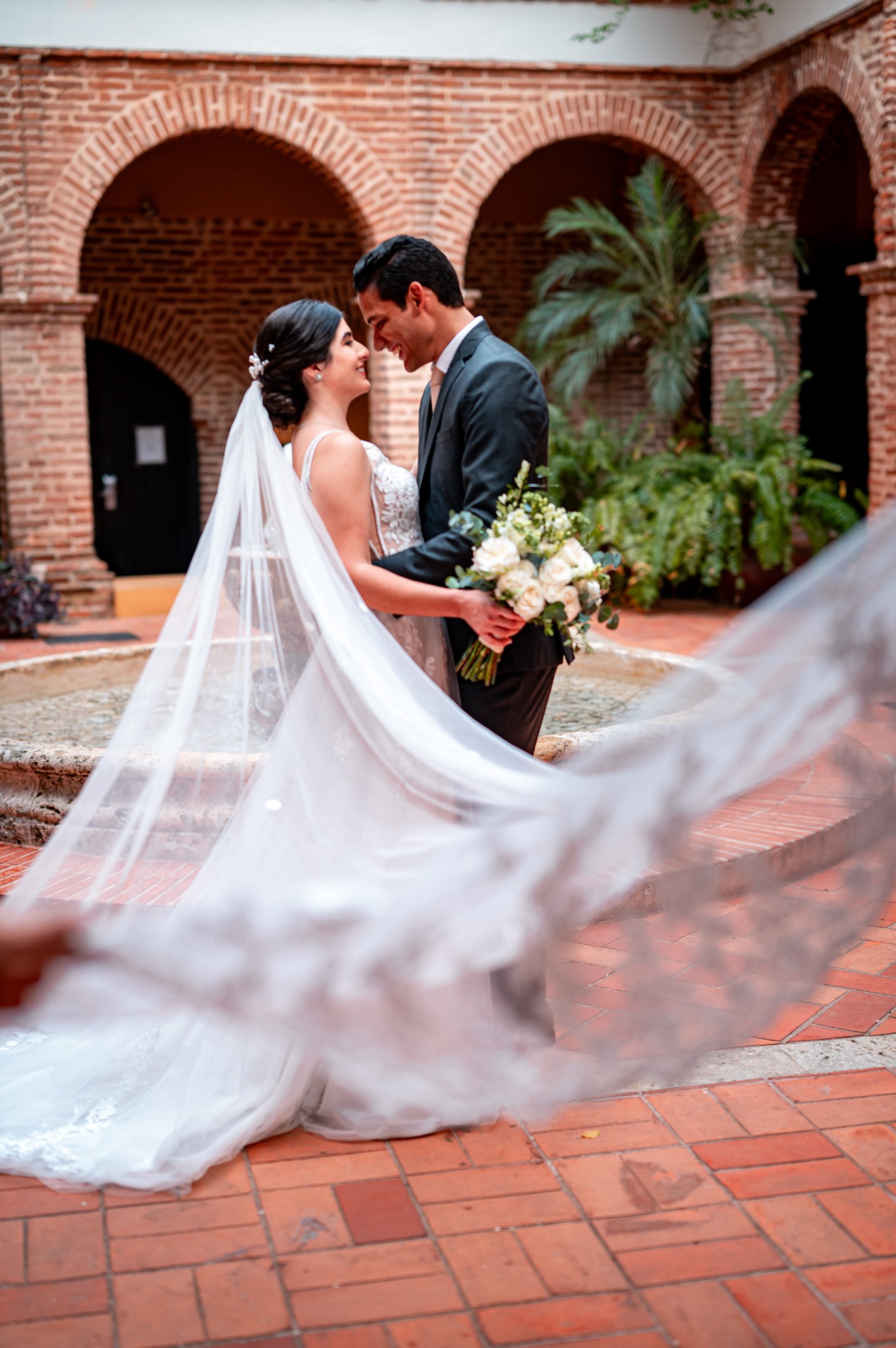 Newlyweds framed by a flowing veil and colonial arches